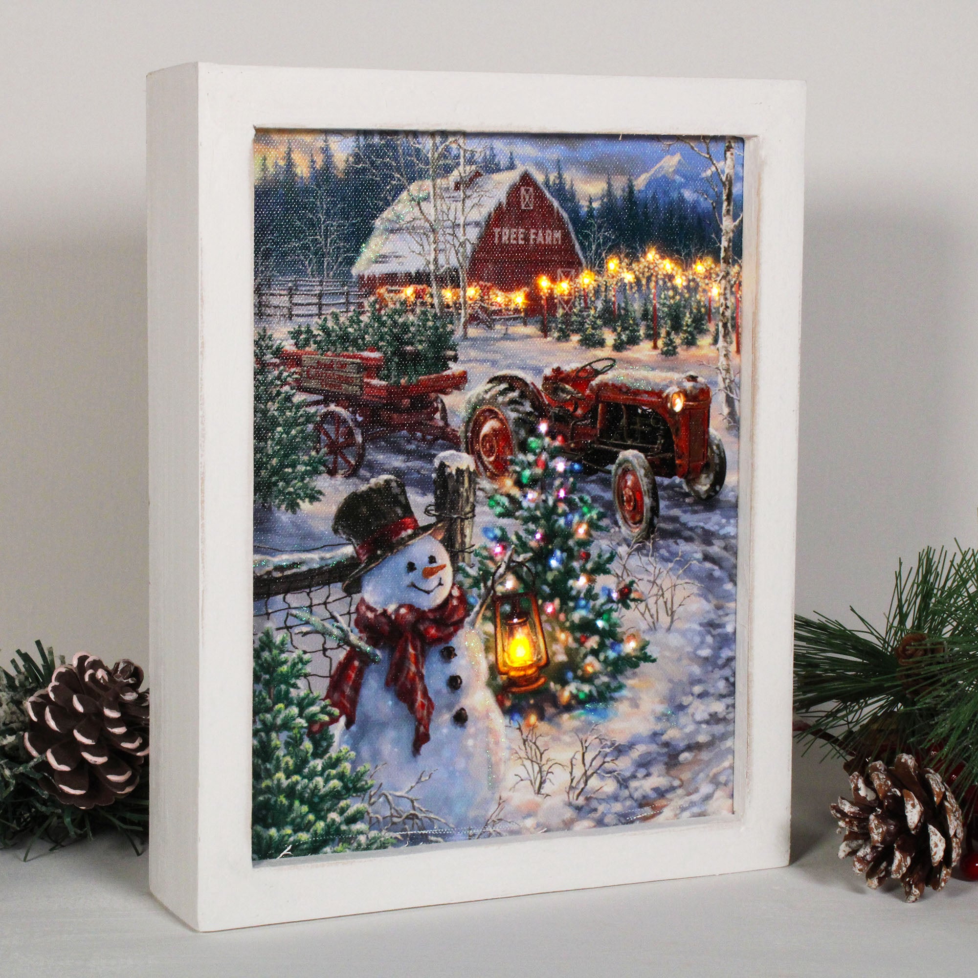 This charming piece features a happy snowman standing proudly amidst a beautiful winter wonderland. Dressed in a top hat, scarf, and carrying a lantern, he's ready to spread joy and cheer.  Behind him, a breathtaking scene unfolds - a picturesque Christmas tree farm filled with rows of stunning evergreens. The closest tree is adorned with bright, twinkling lights, adding a warm and cozy glow to the scene. And in the distance, a barn and tractor can be seen.