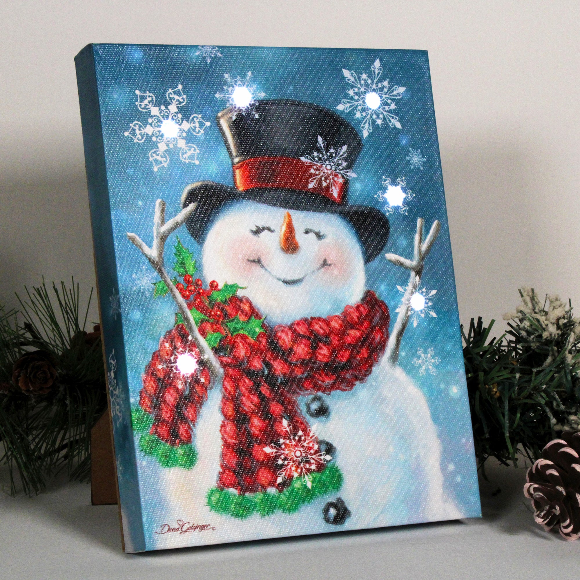 This delightful canvas features a happy snowman with its wooden arms raised in pure joy. Wrapped in a cozy scarf adorned with holly, this snowman is ready to spread some festive cheer.