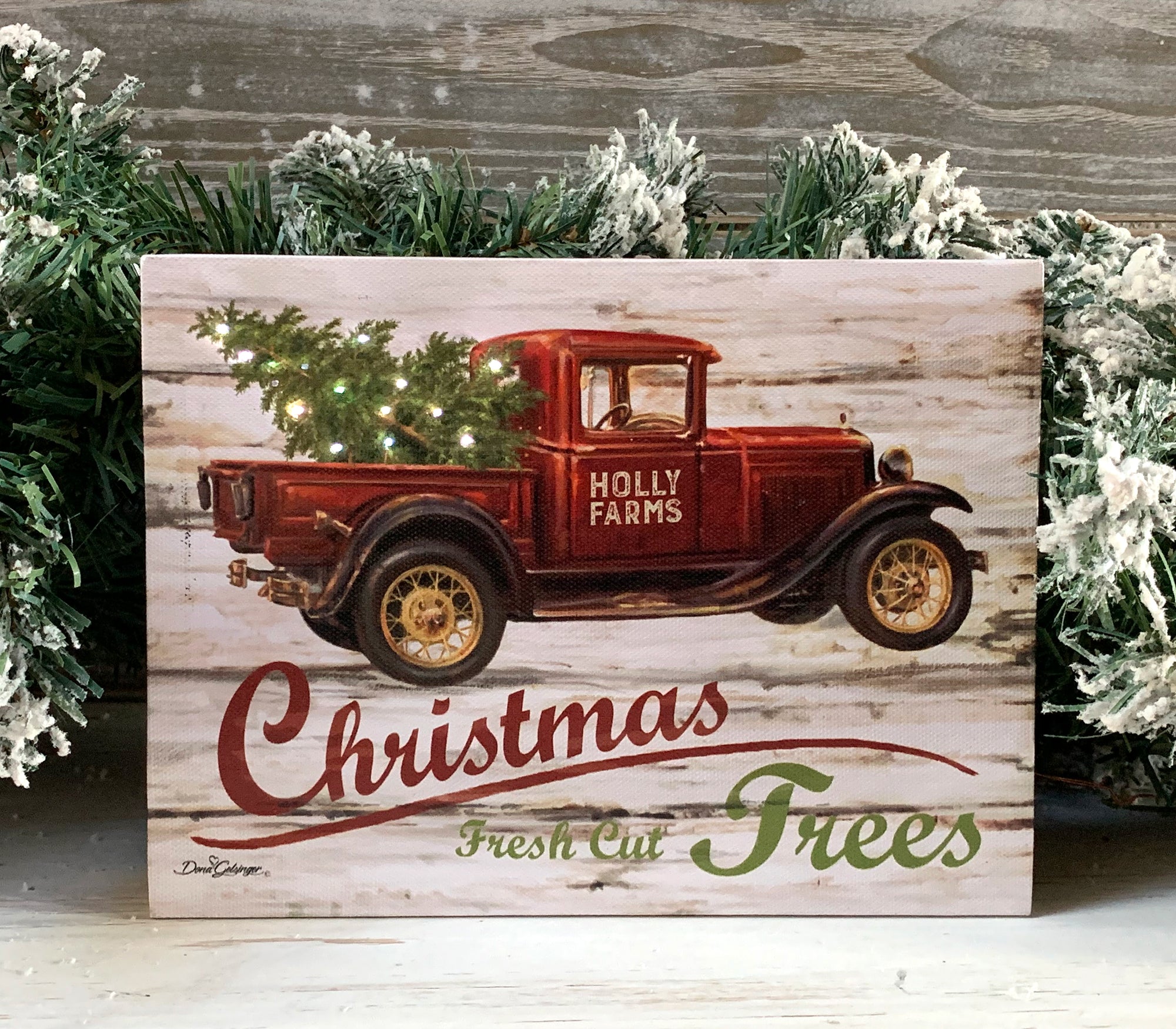 This enchanting piece of art features an iconic old red truck, complete with a fresh cut Christmas tree in the bed and charming lights flickering from it.Beneath the truck, the words "Christmas Fresh Cut Trees"