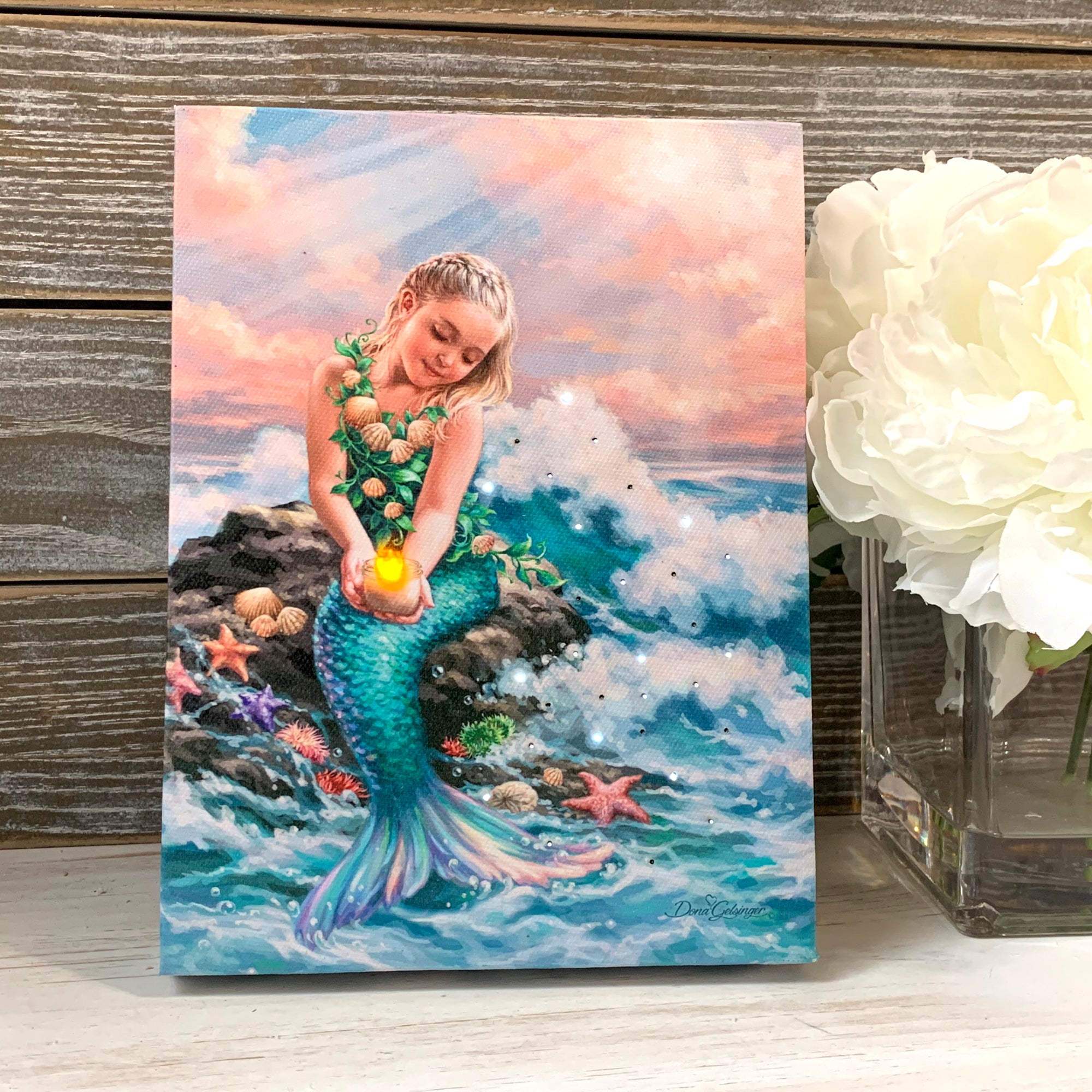 a beautiful young mermaid sits atop a boulder adorned with delicate sea shells, swaying sea anemones, and sparkling star fish. Her eyes light up with joy as she gazes down at the flickering candle in her hand, its gentle glow casting a warm and inviting ambiance all around. The waves crash onto the rock.