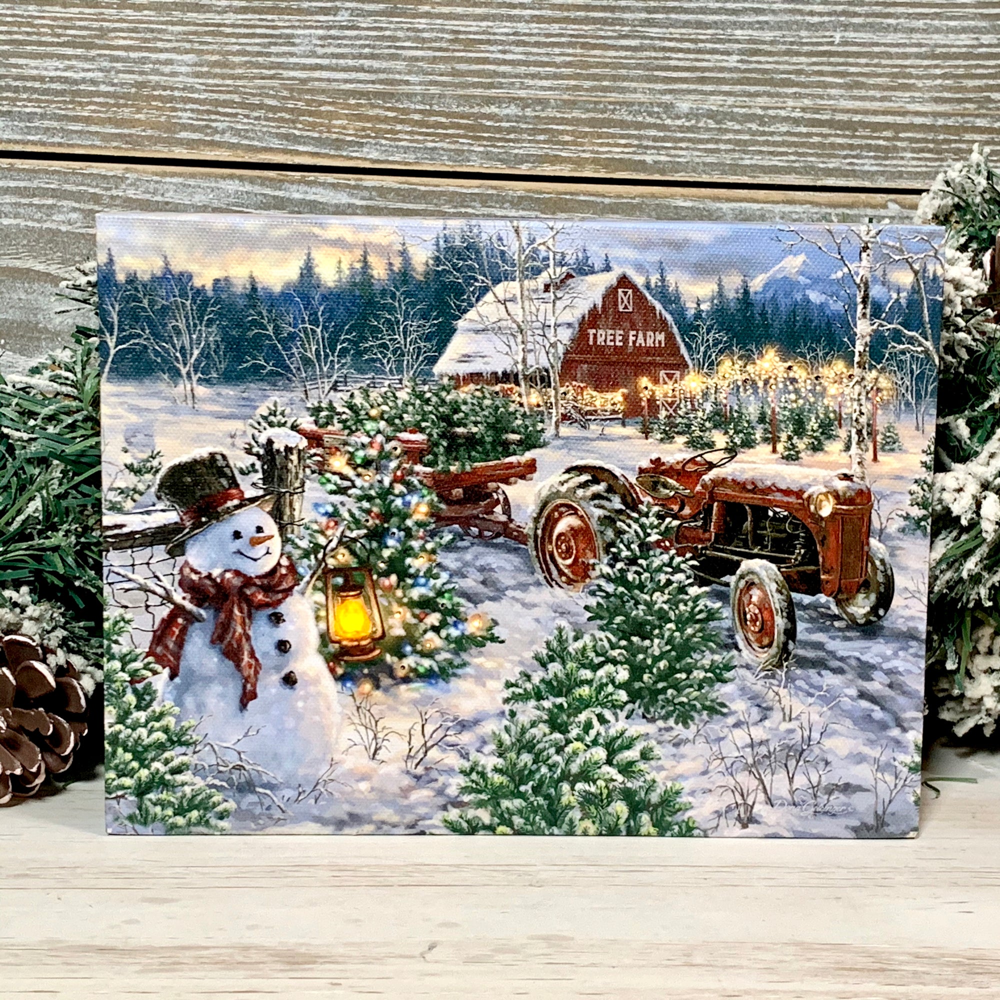 a delightful snowman, adorned in a festive scarf and top hat, standing amidst towering pine trees, holding a glowing lantern that illuminates the snowy landscape.  A rustic red tractor, pulling a trailer filled to the brim with freshly cut trees, adds a touch of whimsy to the scene. The charming barn in the distance, surrounded by trees aglow with sparkling lights, completes the idyllic winter wonderland.