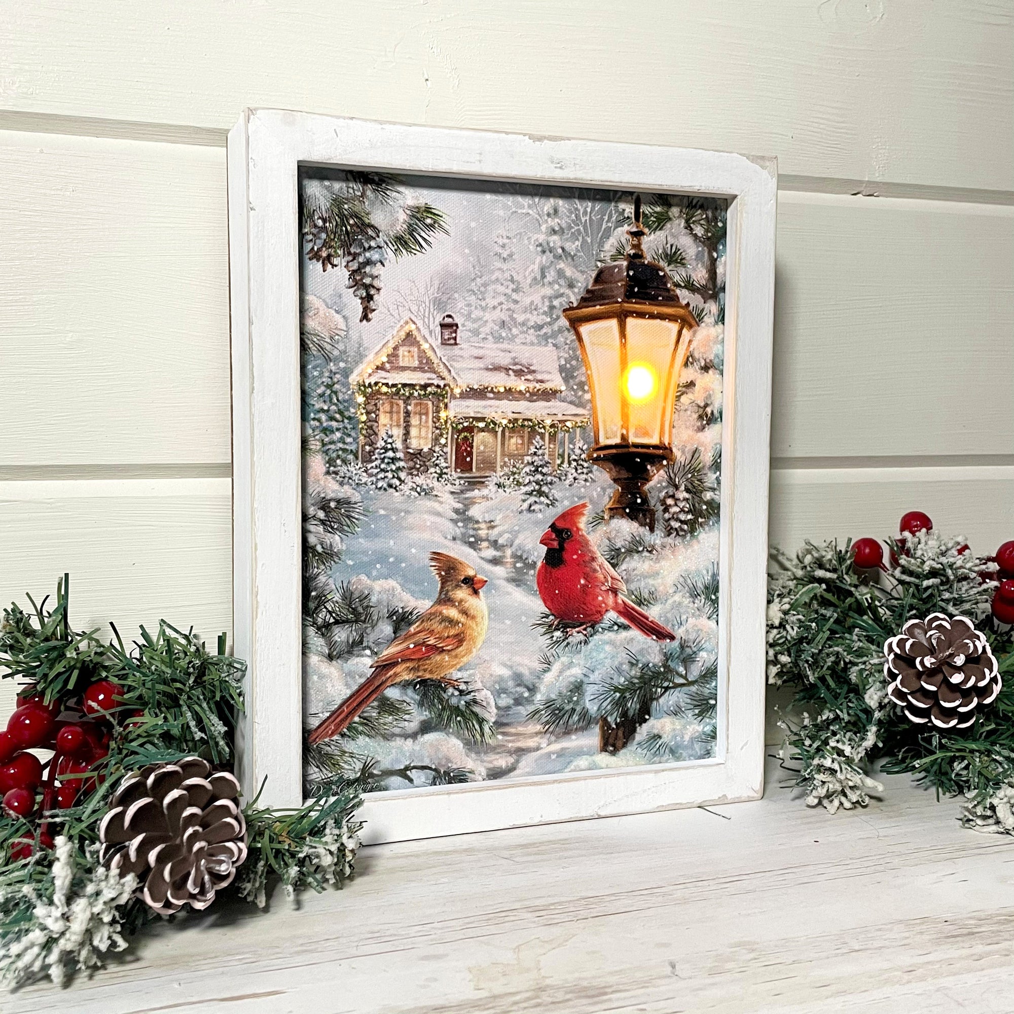 Look no further than our All is Calm Lighted Shadow Box, featuring two beautiful cardinals perched beside a snow-covered lantern, with a cozy cottage in the background.  As the soft glow of the LED lights illuminates this stunning scene, you'll feel transported to a peaceful winter wonderland, where love and serenity reign supreme.