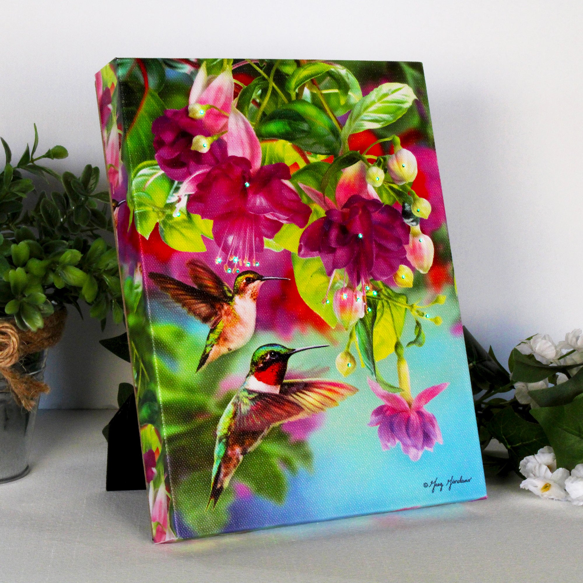 This enchanting canvas showcases two dazzling hummingbirds hovering gracefully in front of a stunning display of fuchsia flowers.