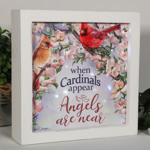  This exquisite piece features two majestic cardinals perched on delicate flower-covered branches, surrounded by a softly glowing light that creates a warm and inviting ambiance in any room.