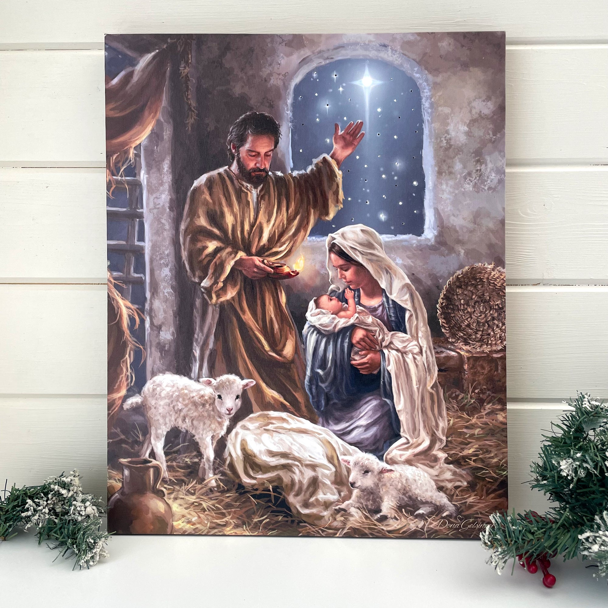 This stunning work of art captures the essence of the momentous occasion as Mary kneels and holds her newborn son in her hands, while Joseph stands above them with a hand raised in worship.  Surrounded by two gentle lambs and bathed in the light of a bright star shining down from above, this beautiful canvas brings the heartwarming story of the nativity to life.