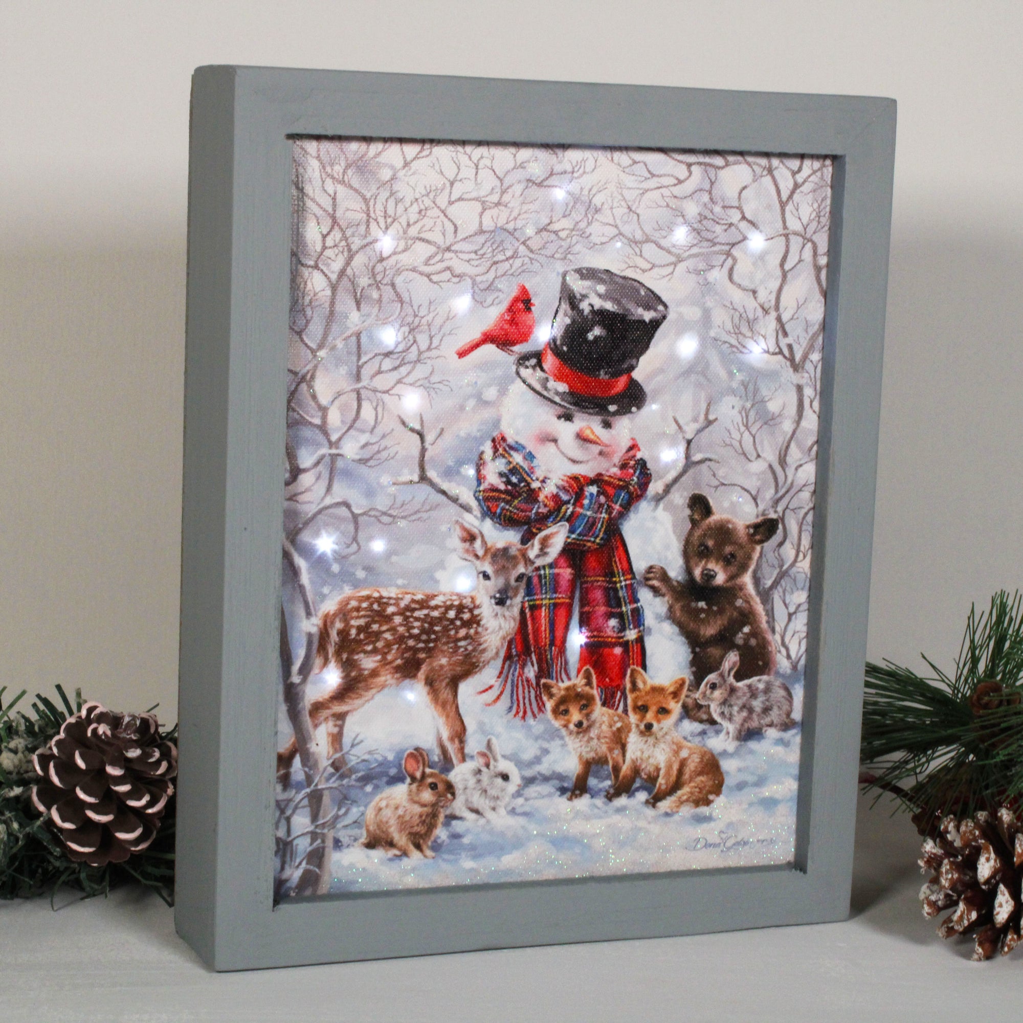 This enchanting piece captures the magic of the season with its stunning snow-covered forest scene and charming cast of characters.  Greeted by a jolly snowman donning a top hat and plaid scarf, you'll be delighted by the company of sweet forest friends. Adorable bunnies, baby foxes, a precious fawn, and even a playful baby bear complete the scene.