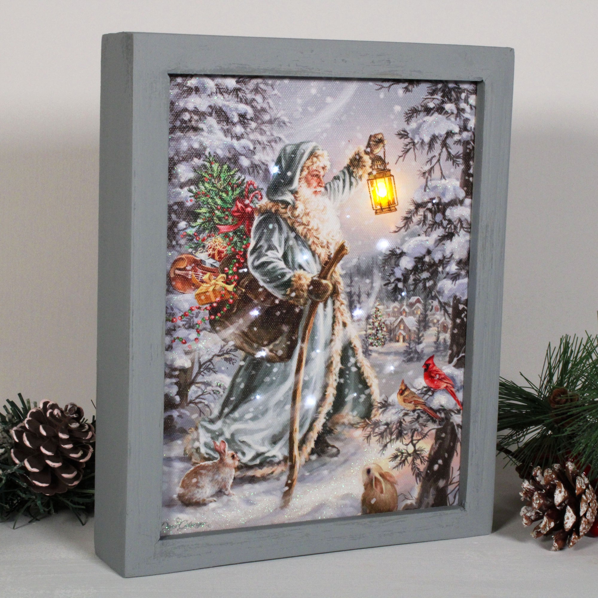 This enchanting piece captures the timeless romance of the holiday season with stunning detail.  In the shadow box, Saint Nicholas can be seen walking through a peaceful forest, his trusty lantern lighting the way as he makes his journey towards the nearby town. His sack of gifts, overflowing with treasures, is slung over his shoulder, ready to bring joy and wonder to all who cross his path.