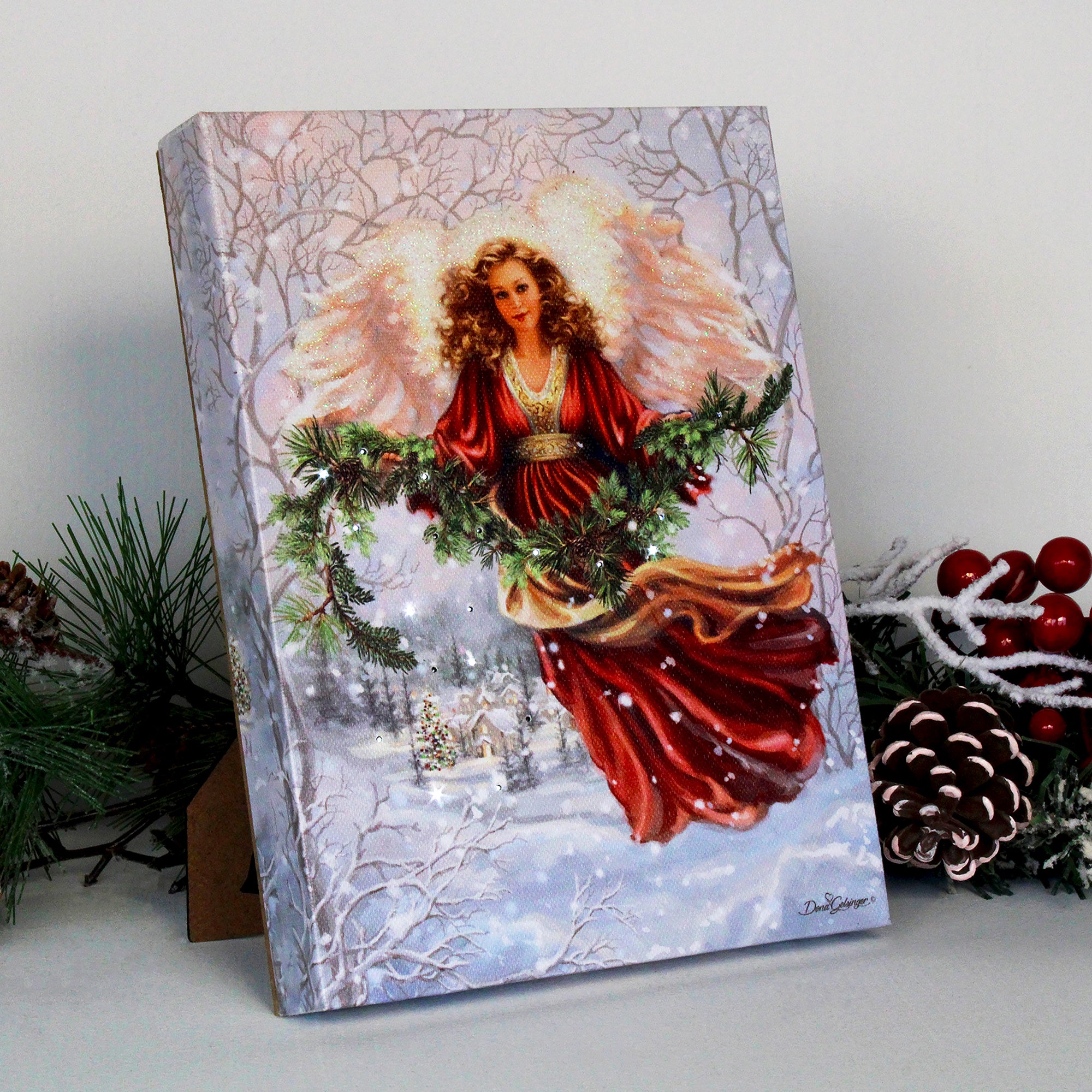 This captivating canvas features an angel dressed in a stunning red gown, with her wings majestically outspread and a garland delicately held in her hand. Behind her, a charming snow-covered town twinkles in the soft light of the falling snow.