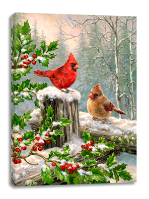 Two majestic cardinals stand tall on a wooden fence, surrounded by a breathtaking snow-covered landscape. Adorned with holly leaves and berries.