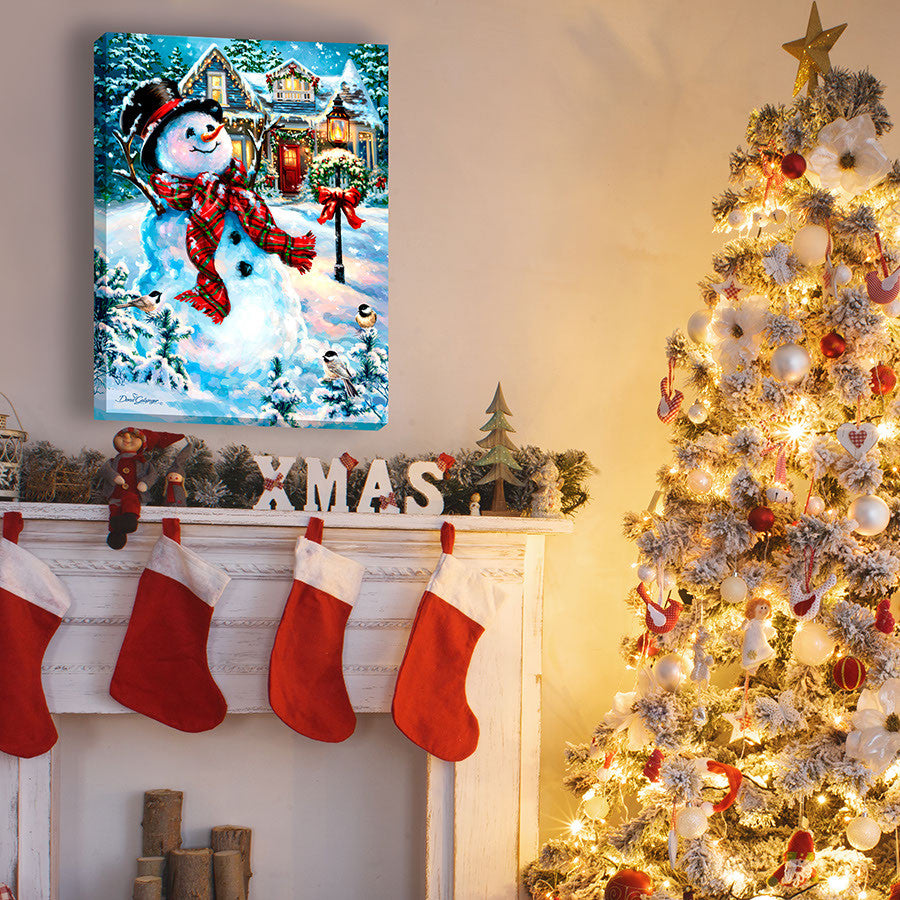 An Old Fashioned Christmas 18x24 Fully Illuminated LED Art. A snowman in front of a snow covered house beautifully staged in a bright room.