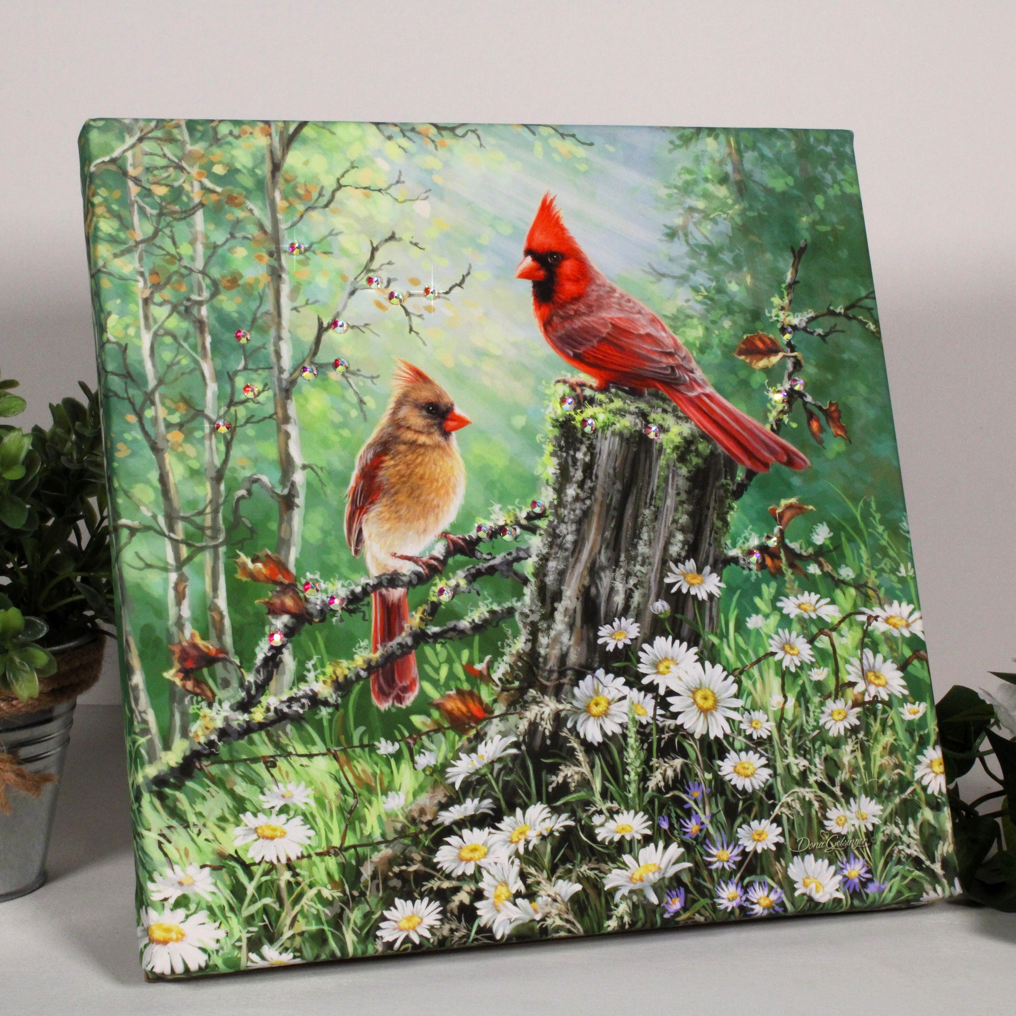 The print captures the essence of romance, featuring two cardinals perched in a picturesque forest. One cardinal gracefully sits on a rustic stump, while the other charmingly rests on a delicate branch surrounded by beautiful daisies.