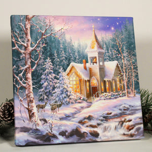 This stunning print captures the essence of winter wonderland with a serene stream in the forefront, and a family of majestic deer in the background.  At the heart of the scene stands a beautiful winter chapel, adorned with glistening snow and twinkling lights, evoking a sense of peace and tranquility.
