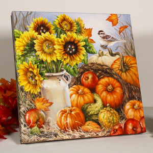  This stunning piece captures the essence of autumn with sunflowers in a charming old-fashioned milk jug and delightful pumpkins, gourds, and apples strewn about.