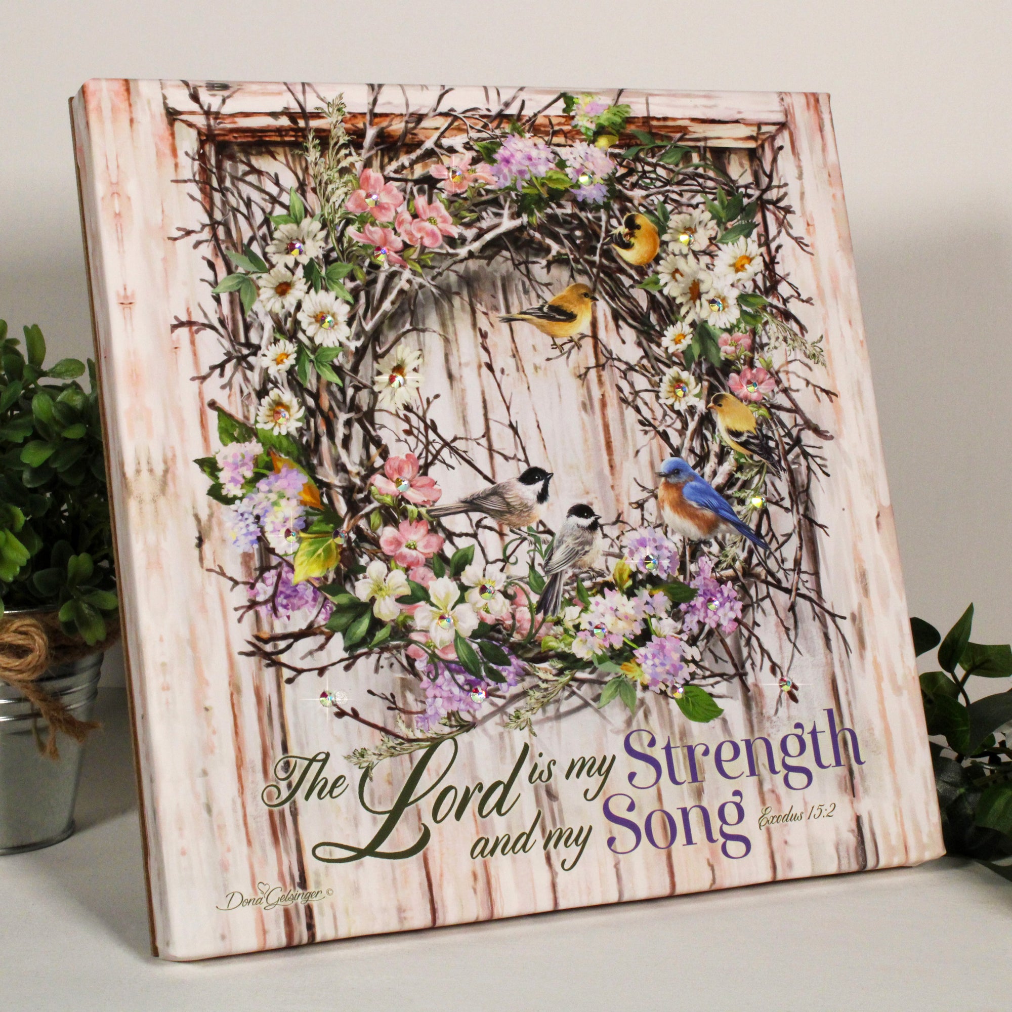 This exquisite wreath is bursting with vibrant multicolored flowers and an array of majestic birds, creating a stunning and uplifting centerpiece for any room.  Beneath the wreath, you'll find the inspiring words of Exodus 15:2.