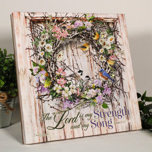 This exquisite wreath is bursting with vibrant multicolored flowers and an array of majestic birds, creating a stunning and uplifting centerpiece for any room.  Beneath the wreath, you'll find the inspiring words of Exodus 15:2.