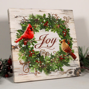 this stunning wreath features a festive blend of pine needles, holly, and pinecones, adorned with two adorable cardinals perched on top.  And the best part? The word "joy" is written in the center of the canvas.