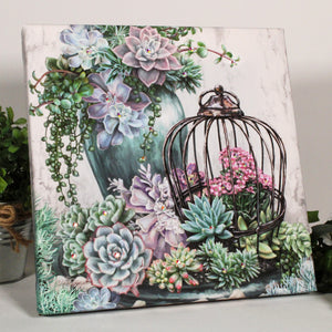 This exquisite piece features an assortment of succulents in varying shades of green, blue, pink, and purple, arranged in a picturesque scene. Some of these captivating plants are nestled within a charming bird cage, while others bloom in a pot, adding depth and texture to the already mesmerizing arrangement.