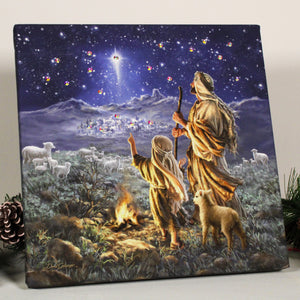  This stunning print captures the serene beauty of a shepherd and his son gazing up at the heavens, awestruck by a shining star that illuminates the night sky. The warmth of the fire and the gentle presence of a lamb create a sense of peace and tranquility that will transport you to a simpler time.