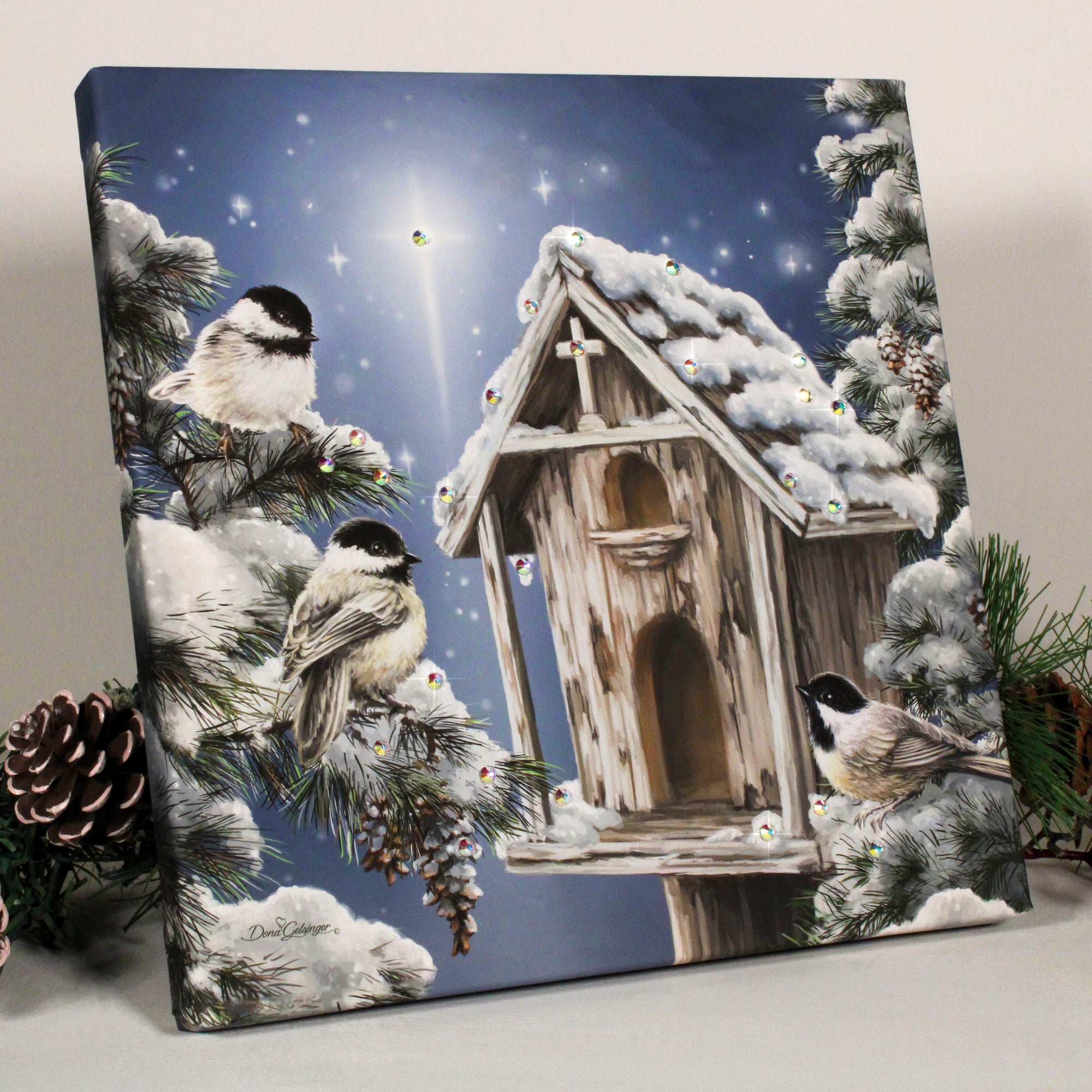 This stunning piece of art features a charming birdhouse nestled among towering pine trees, with a glittering cross at its peak, evoking a sense of spiritual harmony.  The scene is breathtakingly beautiful, with a blanket of snow covering the birdhouse and the pines. Three adorable birds sit perched among the branches, enjoying the peaceful surroundings. And to top it all off, a bright star twinkles in the sky.