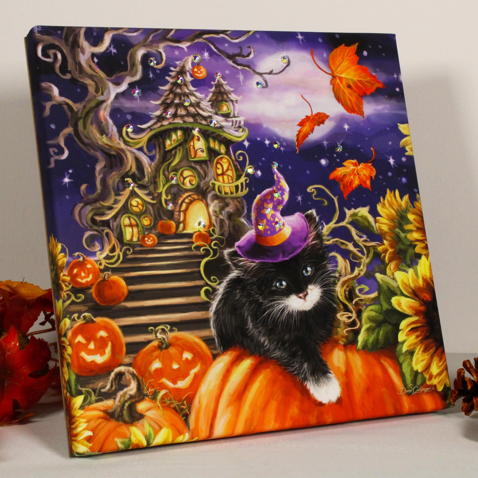 This delightful artwork features a mischievous kitten sporting a witch's hat as she lounges atop a grinning jack-o-lantern surrounded by vibrant sunflowers and more jack-o-lanterns. And to add even more sparkle and shine to this whimsical piece, it's adorned with dazzling crystals that catch the light and add a touch of elegance.