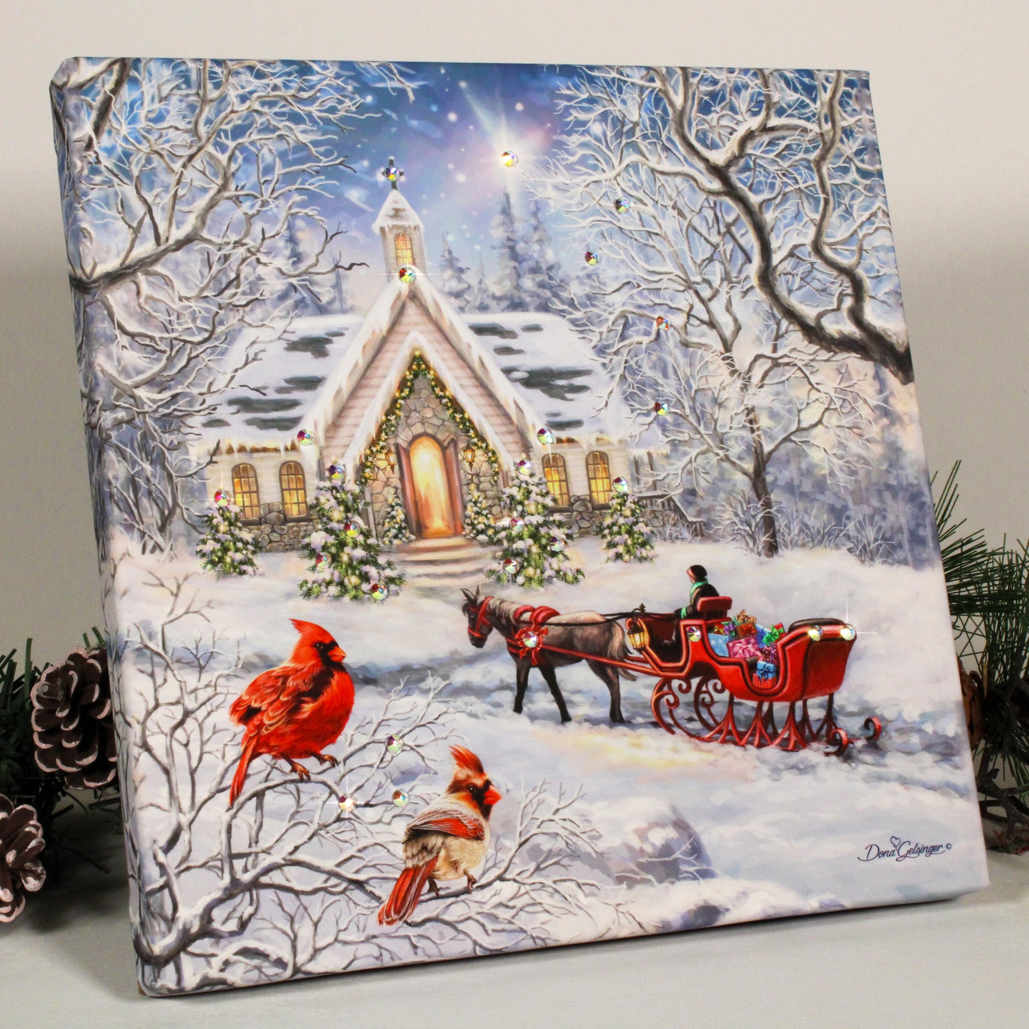Experience the magic of the season with A Christmas Journey Pizazz Print with Dazzling Crystals! This enchanting piece captures the essence of the holiday with its stunning depiction of a red horse drawn carriage in front of a charming chapel.