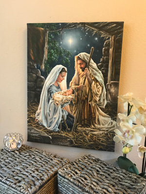 This stunning piece captures the essence of the Christmas story with Mary cradling baby Jesus in her arms, while Joseph gazes upon them in wonder.  As they kneel in the humble manger, the star above shines brightly, illuminating the holy scene with a heavenly glow. 
