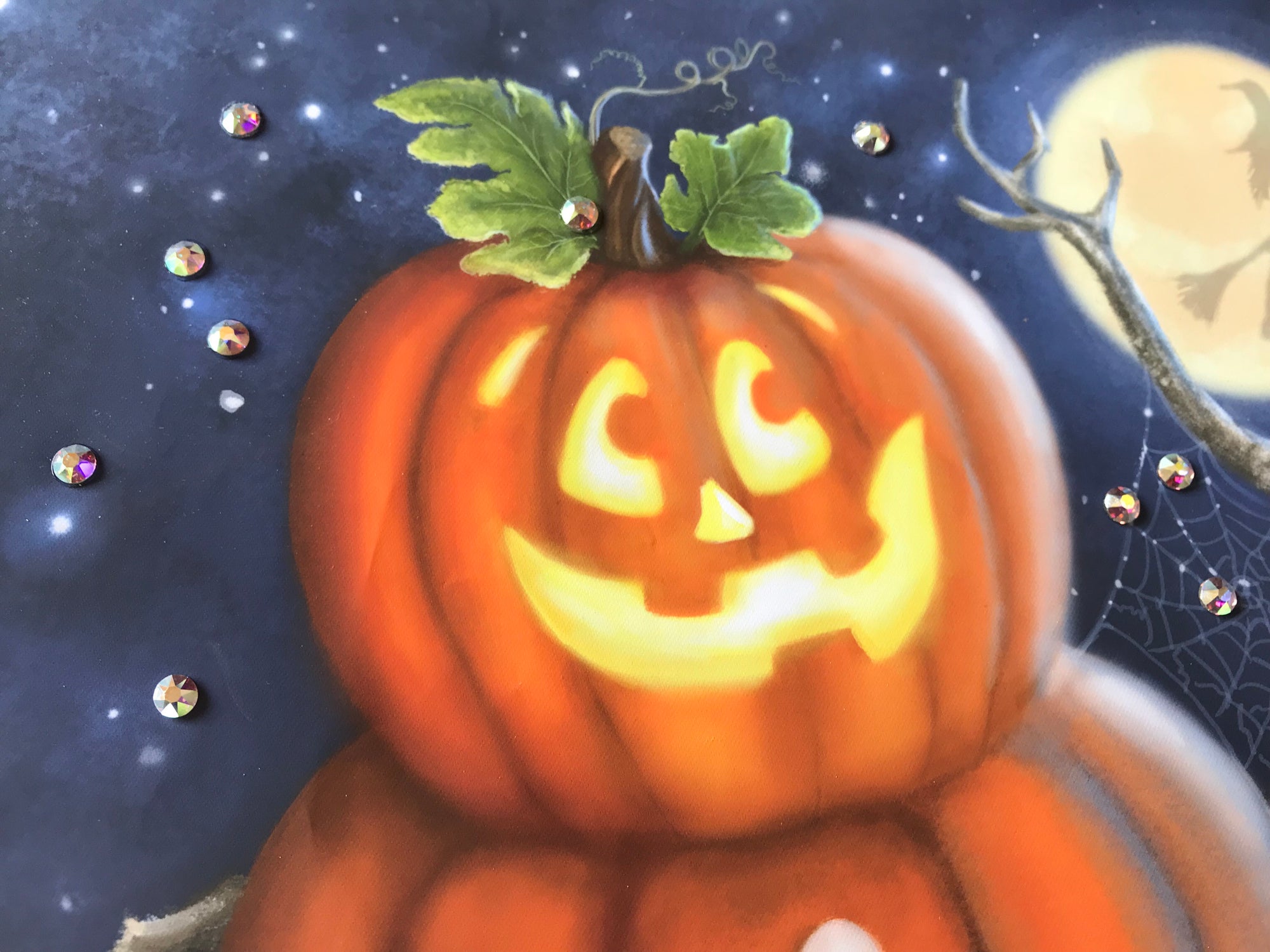 This delightful print features a whimsical jack-o-lantern perched on top of two plump pumpkins, creating a playful snowman-like figure that is sure to bring a smile to your face.  Guiding your way to the sweetest treats is a charming sign that reads "treats this way," adding a touch of magic to this already delightful scene. The backdrop of a full moon casts a romantic glow, while the silhouette of a witch flying on her broomstick across the moon.