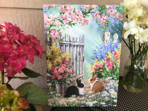 Bring the beauty of nature and the sweetness of love into your home with our Blossoms and Bunnies Canvas Wall Art. Featuring two adorable bunnies sitting amidst a lush flower garden