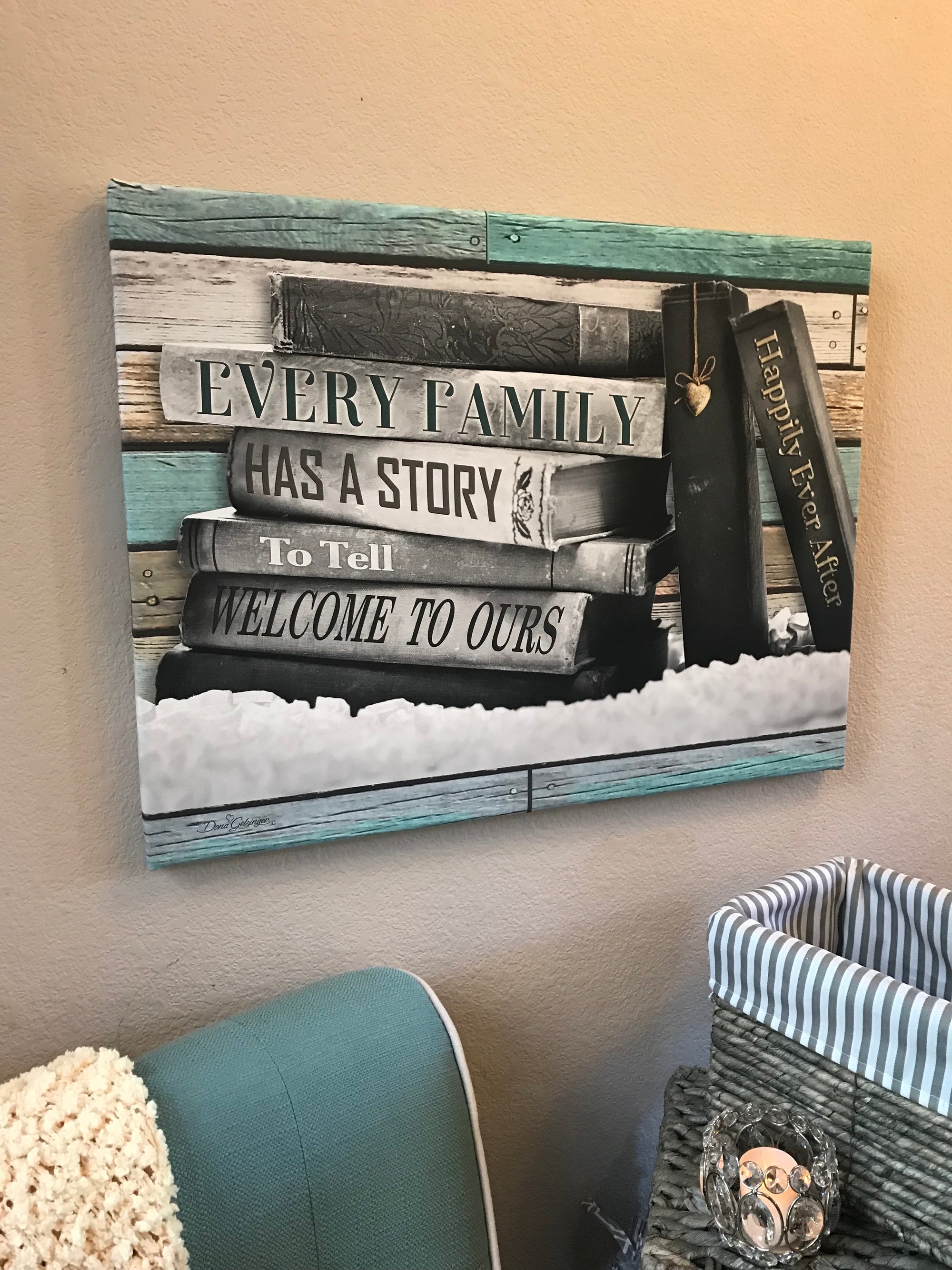 In front of the wall sits a charming stack of books, each one showcasing a word or two that tells your unique tale. "Every family has a story to tell, welcome to ours" is beautifully written on the stack, inviting your guests to learn more about your wonderful journey together.