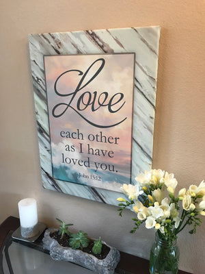 Featuring the timeless words of John 15:12, "Love each other as I have loved you," this piece of art is a beautiful reminder of the power of love.  Set against a serene backdrop of a crashing wave